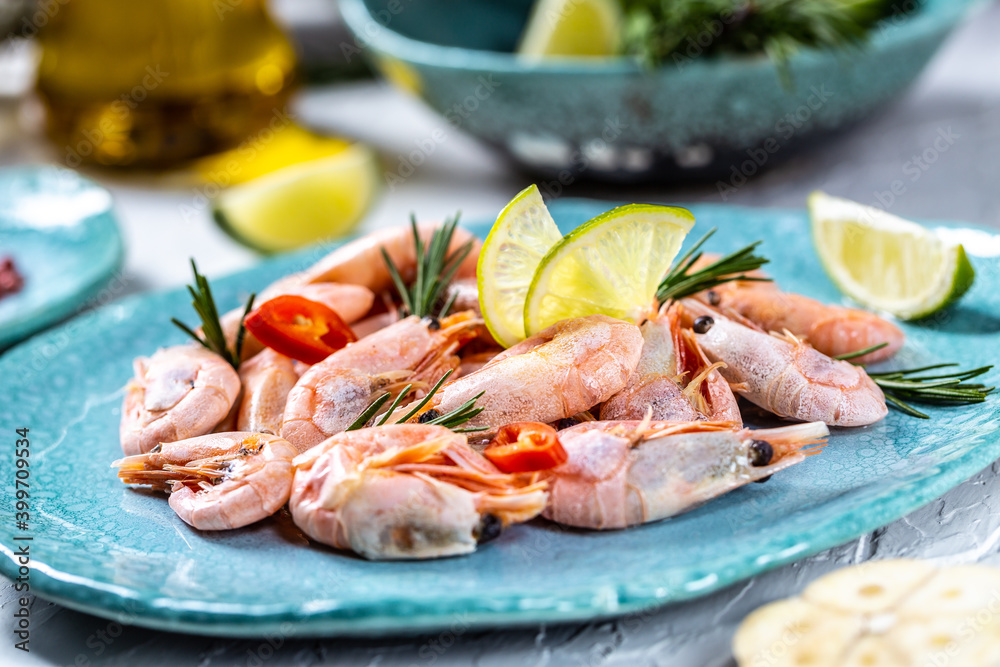 boiled tails of king shrimps served with lime, rosemary, chili on a blue plate, Seafood. Food recipe background. Close up boiled tails of king shrimps served with lime, rosemary, chili on a blue plate, Seafood. Food recipe background. Close up