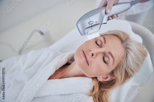 Charming blonde Caucasian woman taking skin care in cosmetology clinic photo
