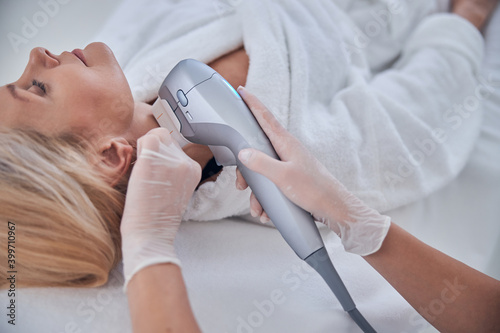 Charming adult business lady receiving ultra former massage neck in dermatology clinic