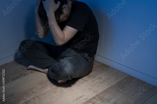 暗い部屋で床に座っている男性