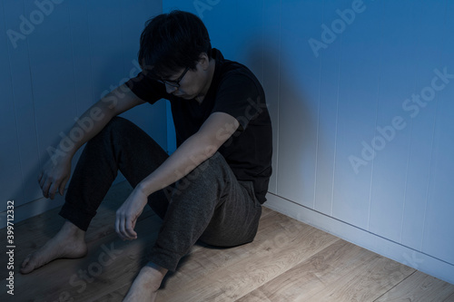暗い部屋で床に座っている男性 © kai