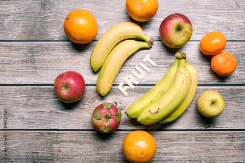 Fruit wooden letters surrounded by autumn tasty fruits on a wooden striped table