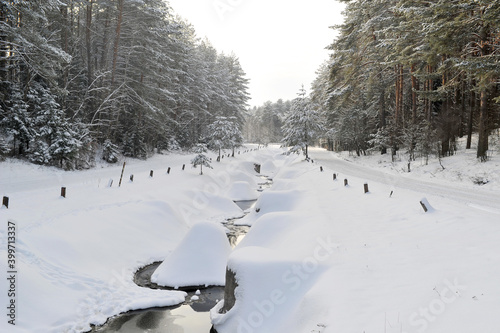 Winter landscape of a mountain river in the snow, around the forest photo