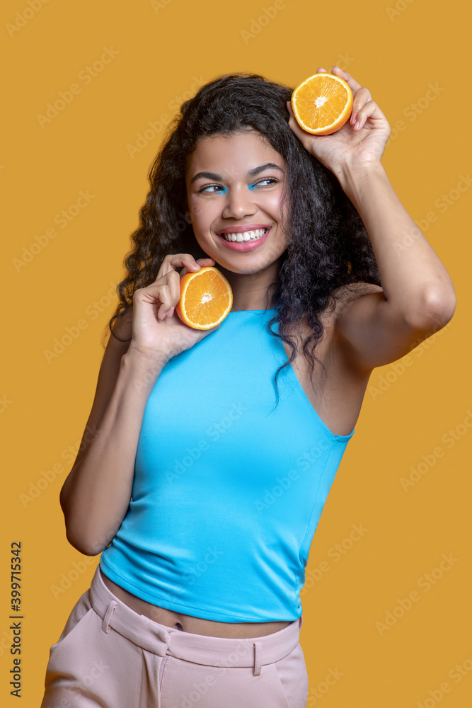 Young dark-haired pretty woman with orange in hands
