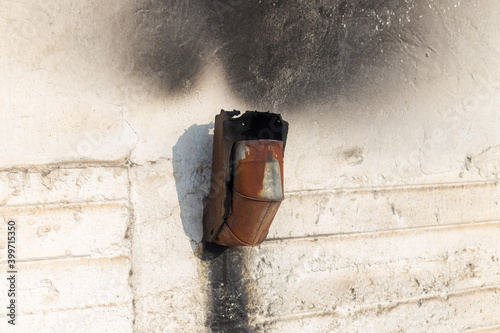 chimney from a coal stove on the wall outside, the white wall darkened from coal smoke