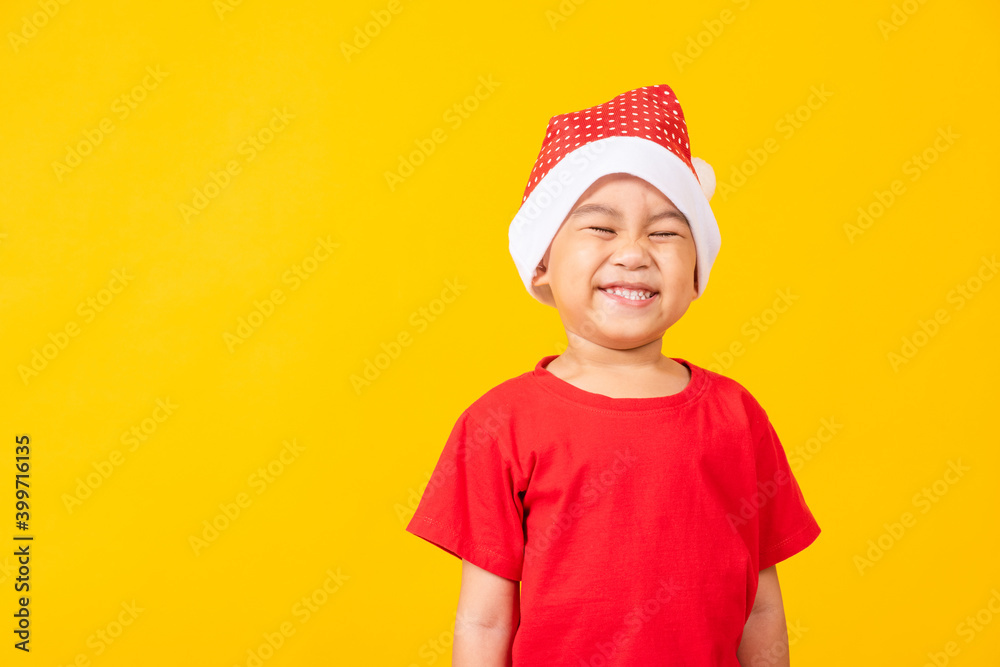 Kid dressed in red Santa Claus hat, Portrait of Asian little cute boy smile and excited the concept of holiday Christmas Xmas day or Happy new year, studio shot isolated on yellow background Kid dressed in red Santa Claus hat, Portrait of Asian little cute boy smile and excited the concept of holiday Christmas Xmas day or Happy new year, studio shot isolated on yellow background