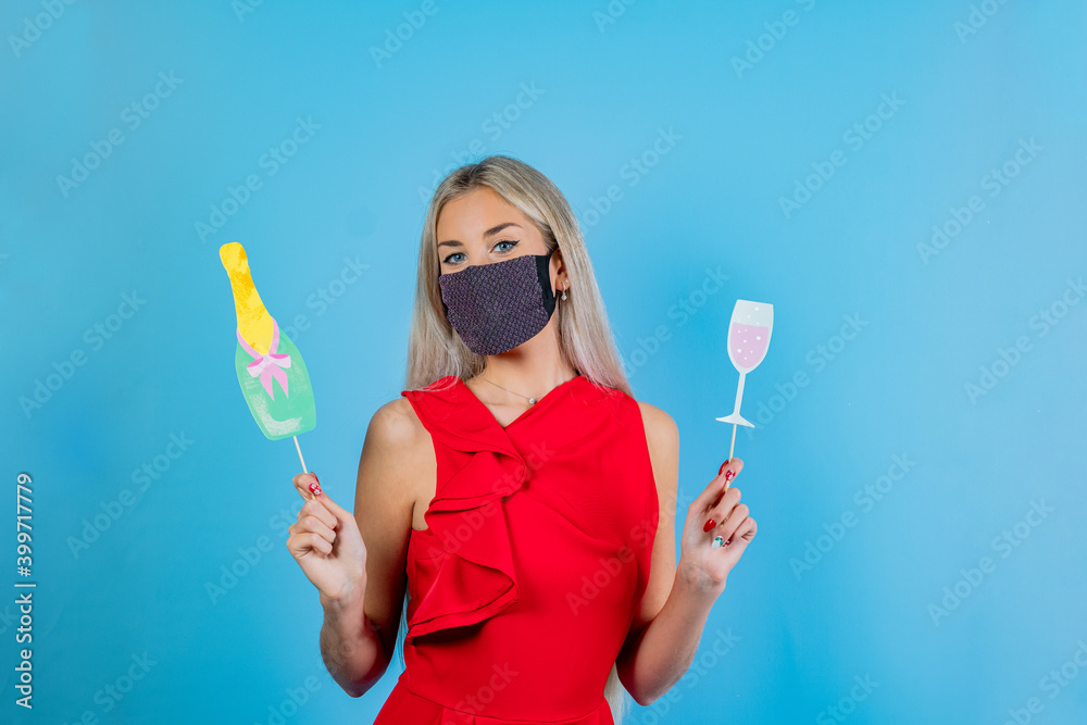 Woman in protective face mask holding a bottle and glass with hand. Party image in pandemic period. Playful young girl celebrating and toast in covid19 time Woman in protective face mask holding a bottle and glass with hand. Party image in pandemic period. Playful young girl celebrating and toast in covid19 time