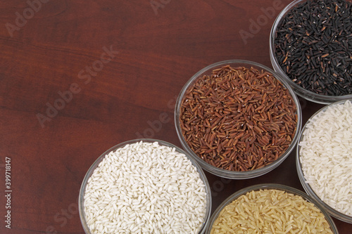 Different kinds of rice in bowls - white, brown, red and black rice.