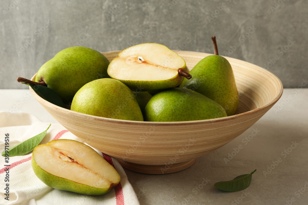 Bowl with green pears and kitchen towel on white textured background Bowl with green pears and kitchen towel on white textured background