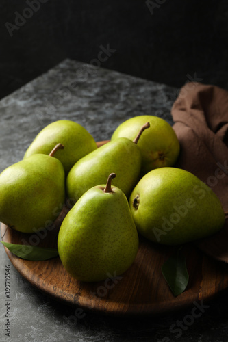 Wooden tray with green pears on black smokey background