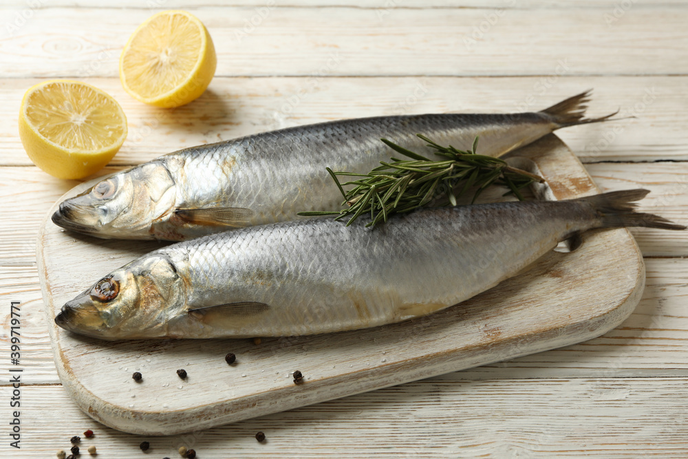 Board with fresh herring fish on white wooden background Board with fresh herring fish on white wooden background