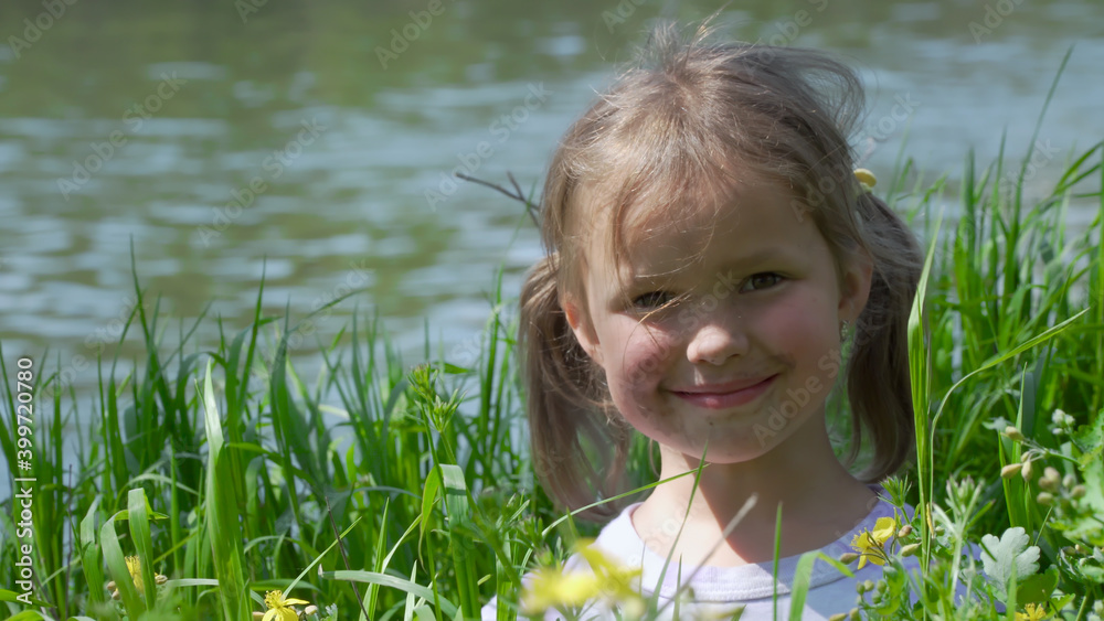 Portrait of a smiling little girl. Baby girl sitting in tall grass. Tiny kid have fun, enjoy nature outdoors. Portrait of a smiling little girl. Baby girl sitting in tall grass. Tiny kid have fun, enjoy nature outdoors.