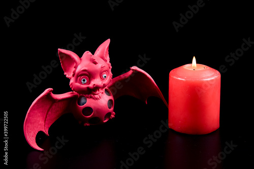Red bat and burning candle. Mystical atmosphere of witchcraft. Magic occult witch ritual. Esoteric concept.