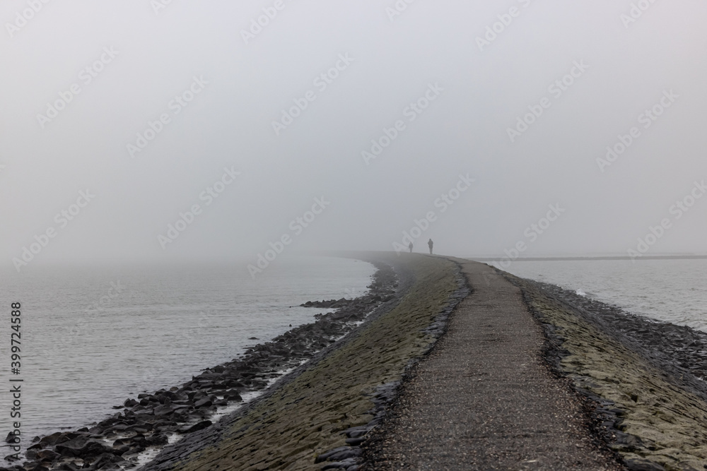 People walking in mist in a distance on a North Sea walkway