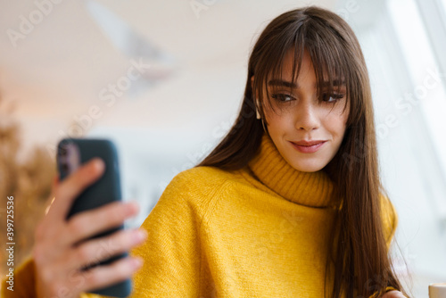 Charming happy girl taking selfie on mobile phone and smiling