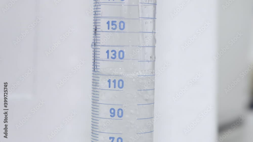 Filling of measuring cylinder. Cylindrical lab glassware showing measurement of liquid level on a scale. Filling of measuring cylinder. Cylindrical lab glassware showing measurement of liquid level on a scale.