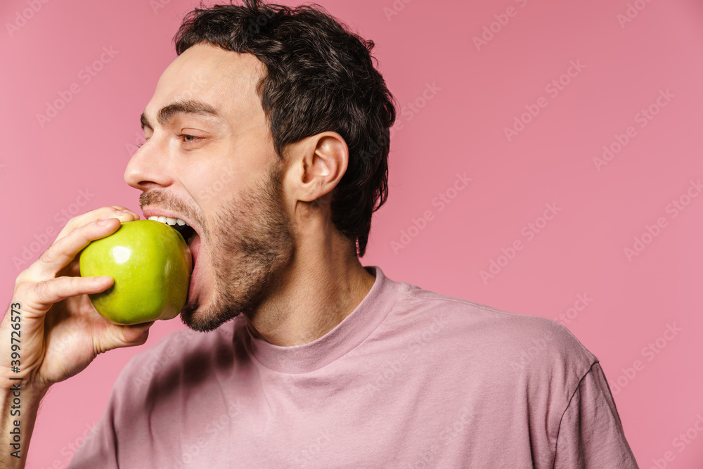 Happy handsome unshaven guy eating green apple Happy handsome unshaven guy eating green apple