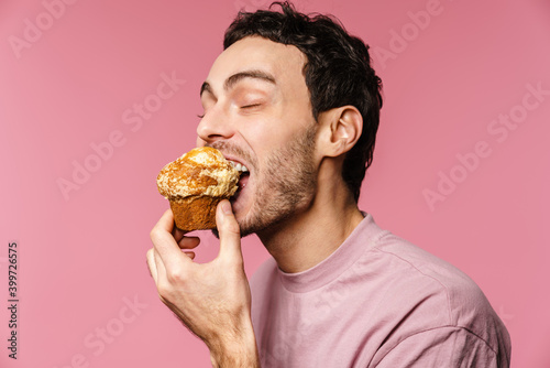 Canvas Print Happy handsome guy eating muffin with eyes closed