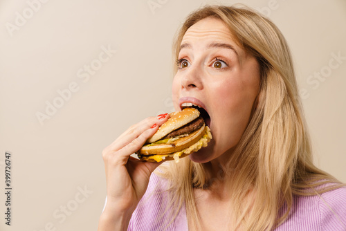 Surprised beautiful hungry girl eating hamburger on camera