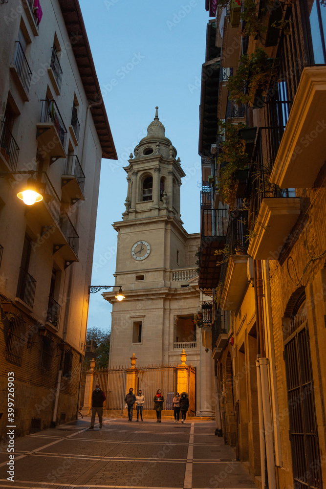 between the houses you can see the tower of the church of Pamplona. It gets dark and the lighting of the streets is warm. Vertical photo