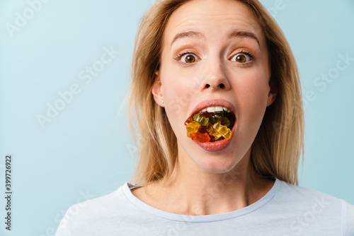 Astonished nice girl posing with teddy gummies in her mouth