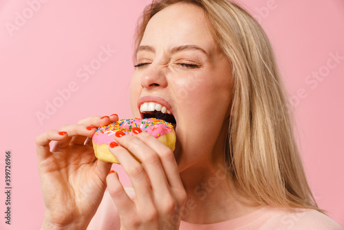 Pleased charming hungry girl eating doughnut on camera