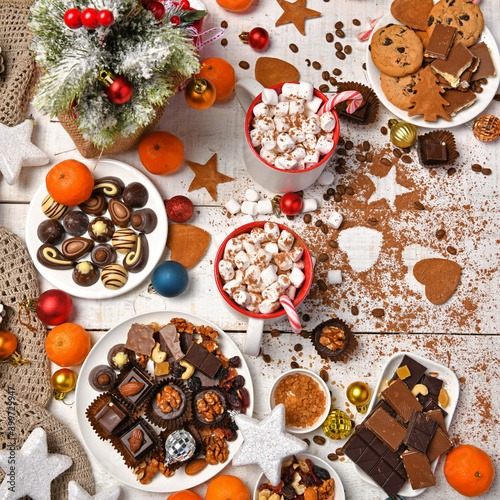 Fototapeta Naklejka Na Ścianę i Meble -  sweet food top view background for merry christmas or new year holiday decoration - chocolate candies, tangerines, cookies, marshmallow and cocoa latte on white wood