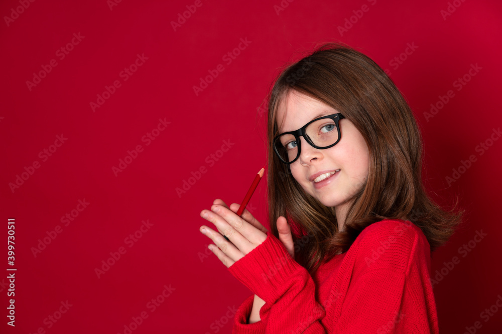 pretty young school girl with glasses and pencil is standing in front of red background pretty young school girl with glasses and pencil is standing in front of red background