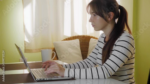 Young beautiful female student is typing on the netbook keyboard, laptop computer. Online training. Coronavisur pandemic, stay home. High quality 4k footage