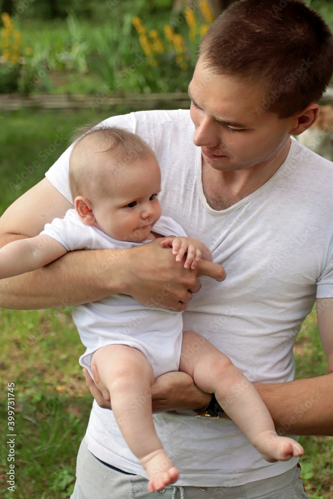 A young guy holds a baby boy in his arms and shows a gentle and warm relationship. A young guy holds a baby boy in his arms and shows a gentle and warm relationship.