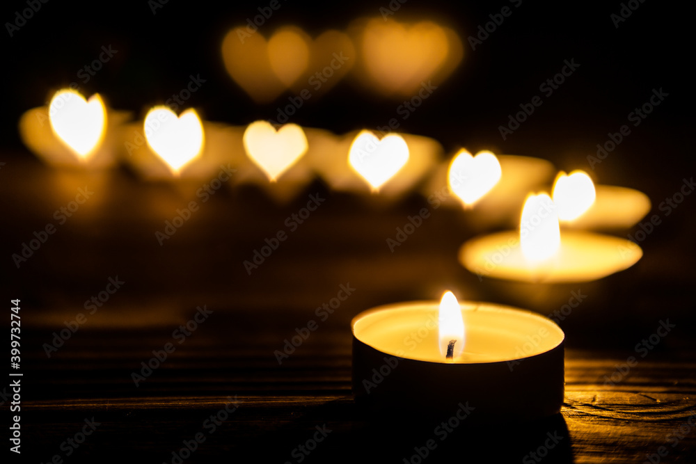 Candles with heart shaped fire are burning in the dark on wooden table. Love and romance concept