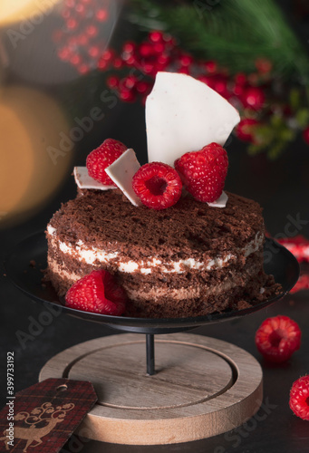 sponge cake three chocolates in a New Year's holiday decoration with raspberries. on dark background