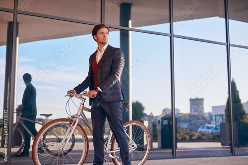Trendy formal guy with bicycle in modern city