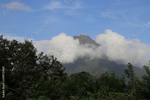Volcano Arenal in some clouds viewed behind trees costa rica