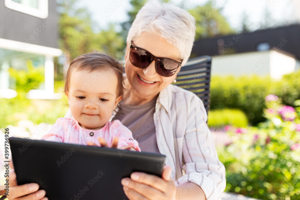family, generation and people concept - happy grandmother and baby granddaughter with tablet pc computer at summer garden family, generation and people concept - happy grandmother and baby granddaughter with tablet pc computer at summer garden