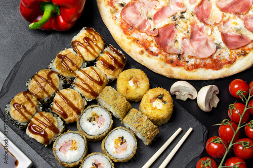 Pizza and sushi rolls tempura and bake rolls on the background of ingredients .Pizza, sushi food photo for menu. Combo set of rolls and pizza.