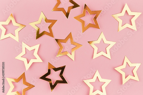 Festive gold glossy stars on pastel pink background  top view  pattern.