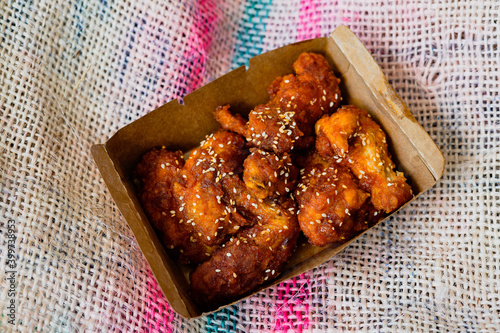 Deep fried chicken wings and drummets coated with hot and spicy Korean sauce in a take away container. photo