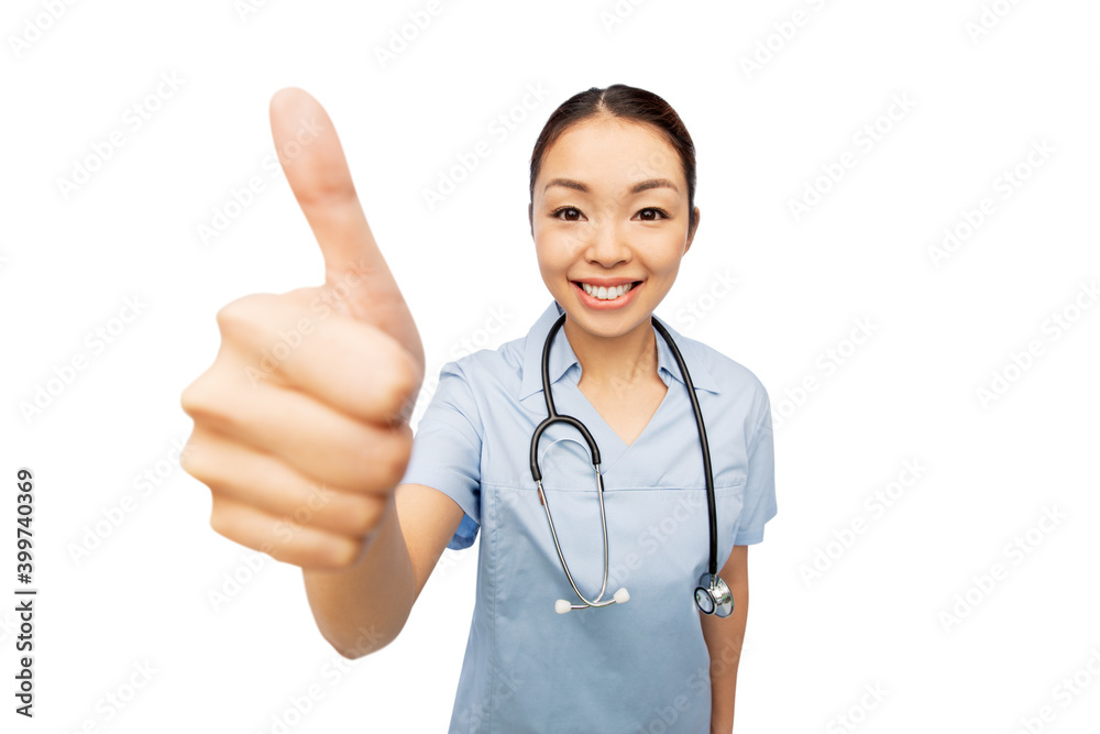 medicine, profession and healthcare concept - happy smiling asian female doctor or nurse in blue uniform coat with stethoscope showing thumbs up over white background medicine, profession and healthcare concept - happy smiling asian female doctor or nurse in blue uniform coat with stethoscope showing thumbs up over white background