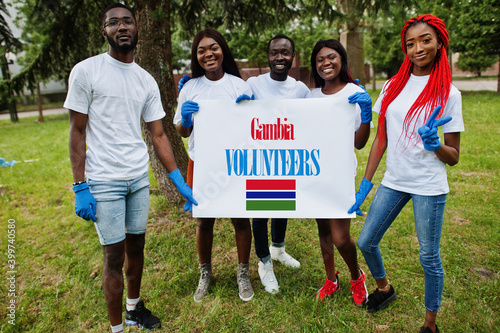 Group of happy african volunteers hold blank with Gambia flag in park. Africa countries volunteering  charity  people and ecology concept.