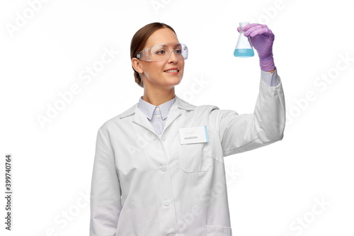 science, chemistry and people concept - happy smiling young female scientist in goggles with chemical in flask making test or research