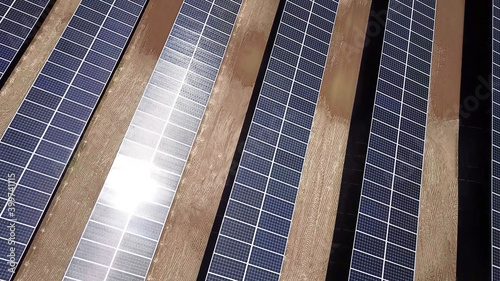 Reflection of sunlight on solar power panels in the desert. aerial top above view of photovoltaic PV modules in solar energy plant farm background