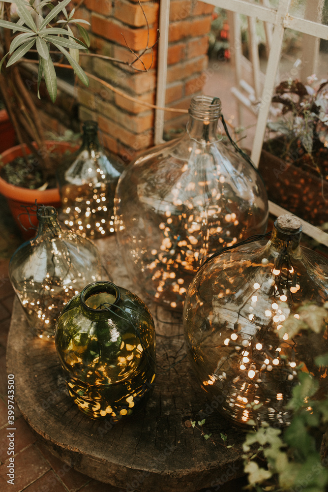 Fototapeta premium Light decorations in big wine bottles. Wedding decor. christmas decoration. Botanical style. 