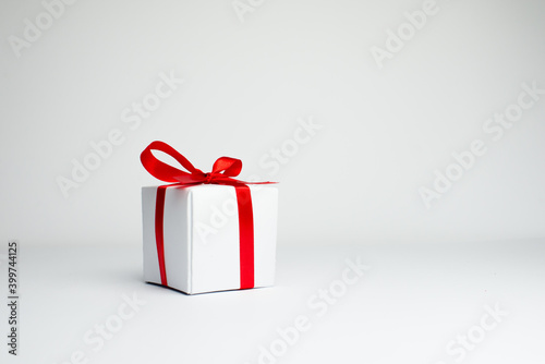 
Festive background. White gift with a red ribbon with white and red christmas balls on a white background. Gift box isolated on white background. Spece for text. Background for Christmas. photo