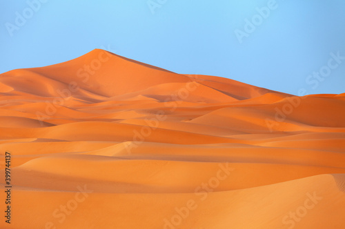 Sand dunes in the desert with blue sky background.