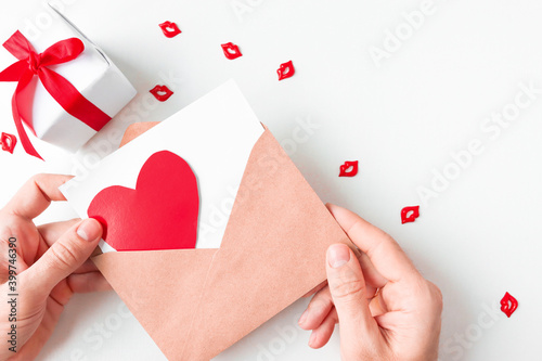Romantic layout-an envelope with a red heart, a gift with a bright ribbon and bright figures of kisses. photo