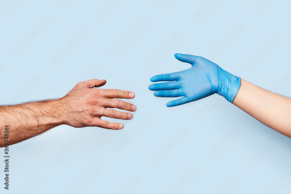The men's hand and the woman's hand in the latex glove are drawn to each other. The photo symbolizes social distance and safety.