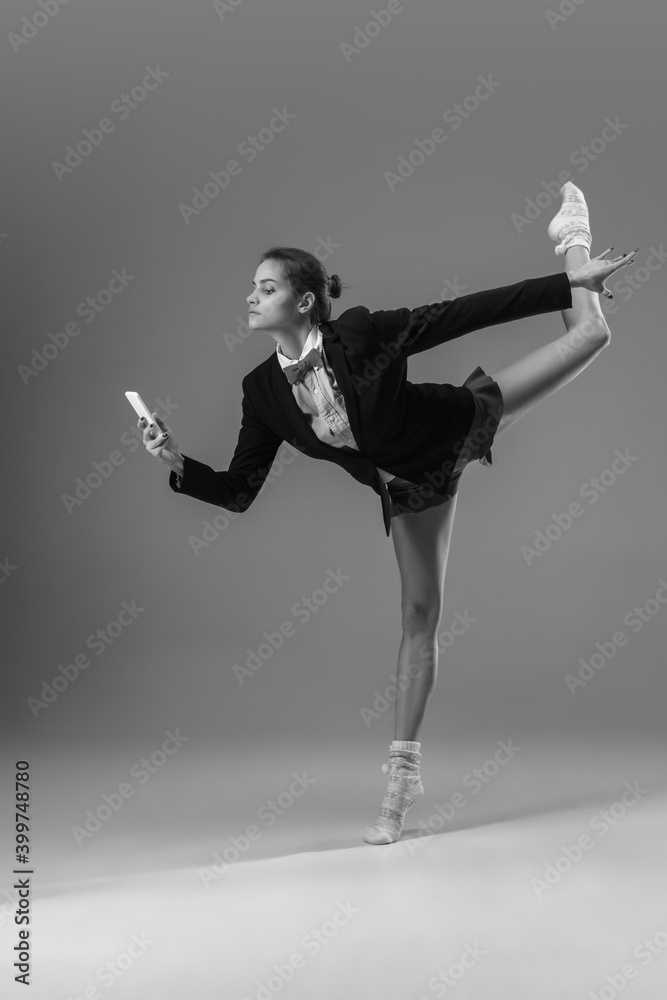 Obraz premium Flexible. Young fashionable, stylish woman wearing jacket and socks working from home. Fashion during insulation 'cause of coronavirus pandemic. Half business and half home style. Black and white.