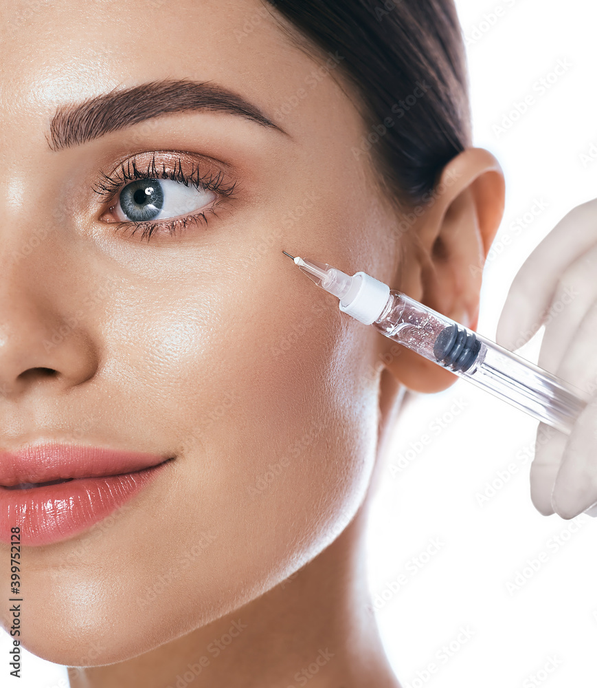 Beautiful woman during facial mesotherapy for smoothing of mimic wrinkles  around eyes. Beautician doing anti-aging injection for rejuvenation and  lift skin Stock Photo