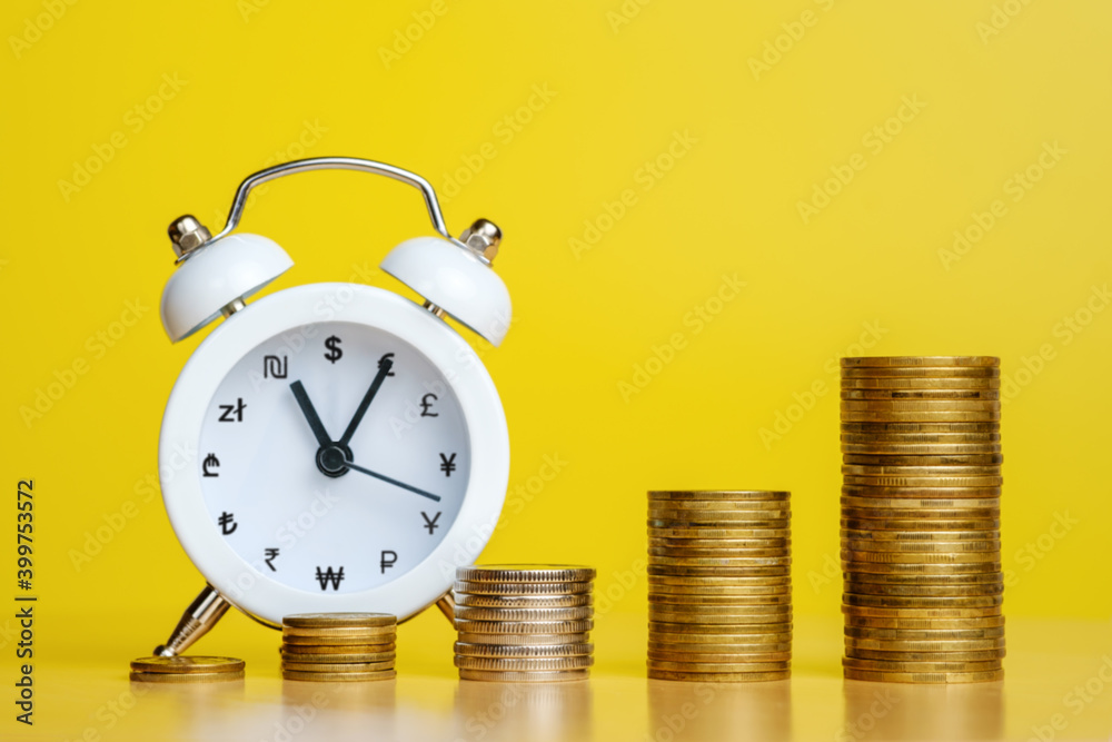 Stacks of coins in row ascending and alarm clock with currency signs instead of numbers. Time is money, efficient business, great income in short time concepts. Copy space for text Stacks of coins in row ascending and alarm clock with currency signs instead of numbers. Time is money, efficient business, great income in short time concepts. Copy space for text